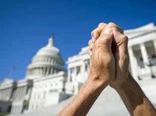 hands clasped together with image of white house in the background