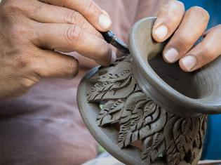 person carving design into wet clay