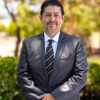 Dr. Roberto Gonzalez standing outside wearing a suit and smiling