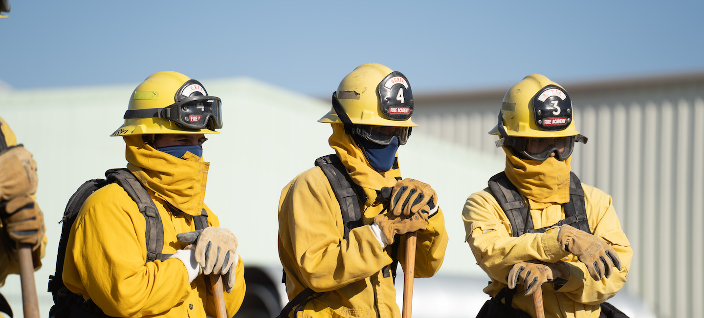Three fire academy students in full firefighter gear and masks. 