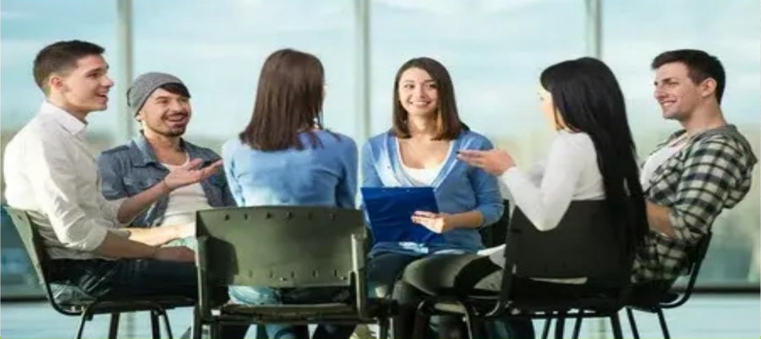 A group of six students sitting in a circle around a table