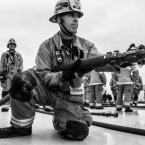 Jack Twitchell in full firefighter garb with a fire hose. 