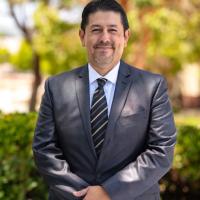 Dr. Roberto Gonzalez standing outside wearing a suit and smiling