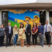 Oxnard College leaders and artists standing in front of new mural on an external wall of Condor Hall.