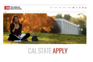 female student sitting on University lawn using cell phone