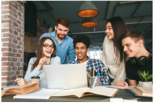 group of 5 students smiling and glancing at laptop 