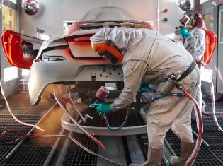 person painting a car in a professional paint booth setting