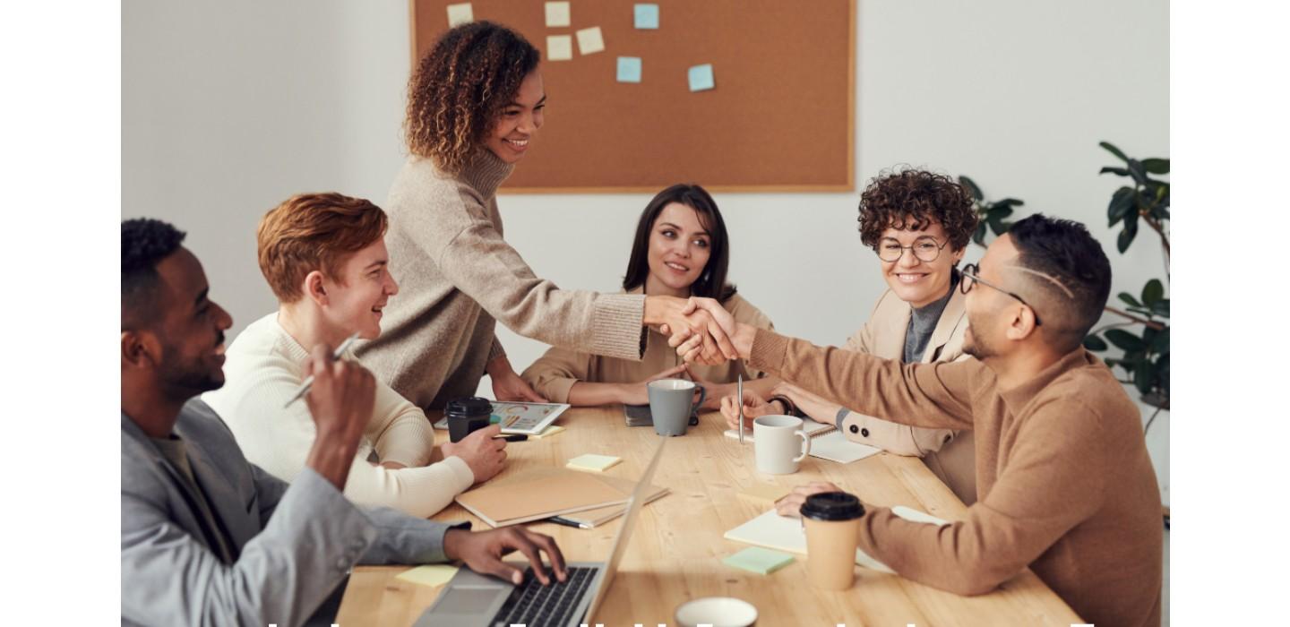 group of people seated at interview table with one person shaking hands with another who is seated