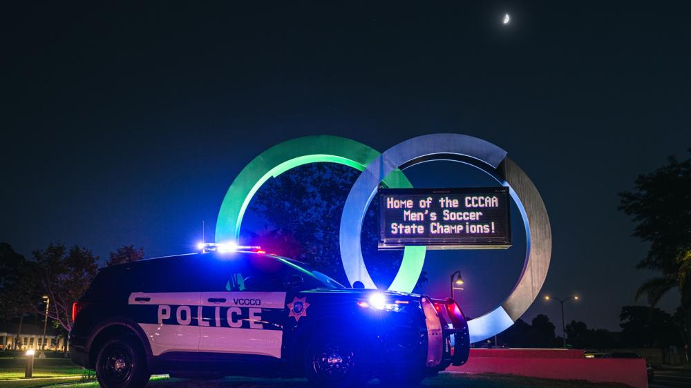 Police Cruiser with lights on next to the OC Marque sign 