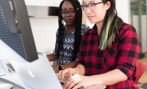 Two women sharing a computer screen.