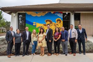 Oxnard College leaders and artists standing in front of new mural on an external wall of Condor Hall.
